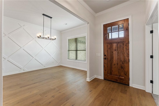 entrance foyer featuring baseboards, a notable chandelier, wood finished floors, and crown molding