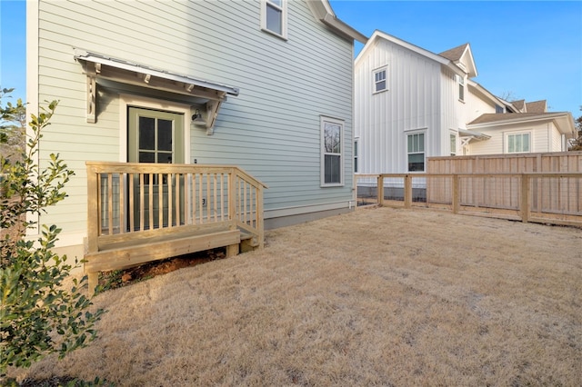 rear view of property with board and batten siding and fence
