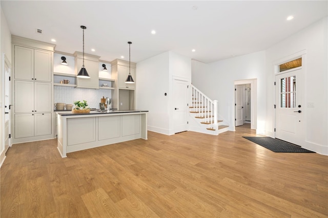 kitchen featuring light wood finished floors, hanging light fixtures, tasteful backsplash, and open shelves