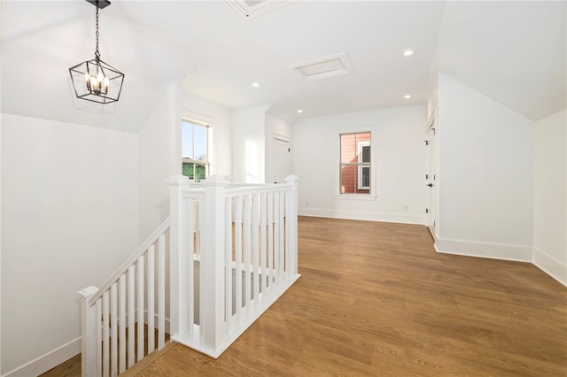 hall with an upstairs landing, plenty of natural light, attic access, and wood finished floors