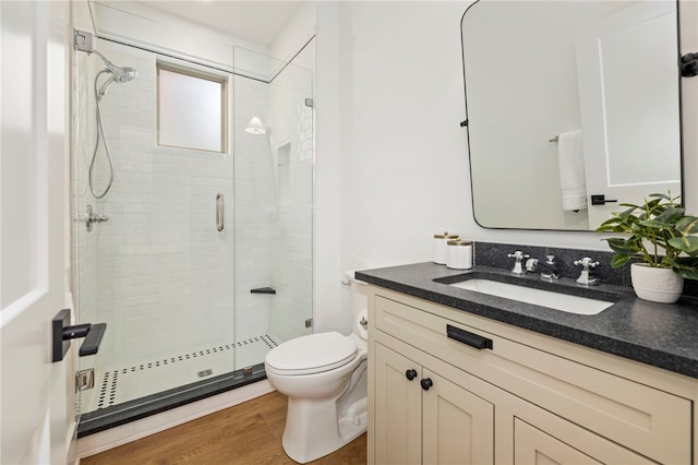 full bathroom with wood finished floors, toilet, a stall shower, and vanity