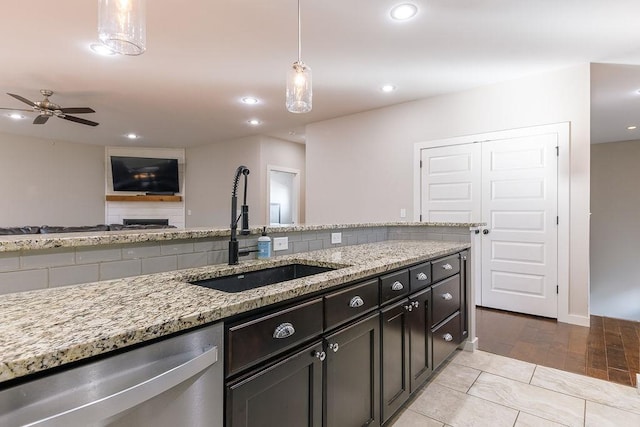 kitchen featuring sink, tasteful backsplash, light stone countertops, decorative light fixtures, and stainless steel dishwasher