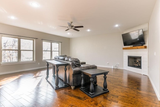 living room with a large fireplace, dark hardwood / wood-style floors, and ceiling fan