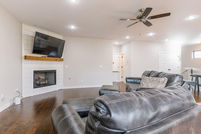 living room featuring ceiling fan, dark wood-type flooring, and a fireplace