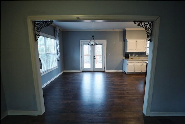 unfurnished dining area featuring crown molding, a healthy amount of sunlight, dark hardwood / wood-style flooring, and french doors