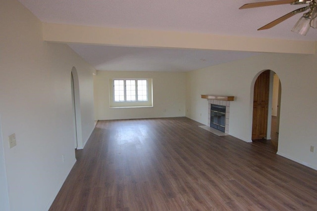 unfurnished living room with dark wood-type flooring, a tile fireplace, and ceiling fan