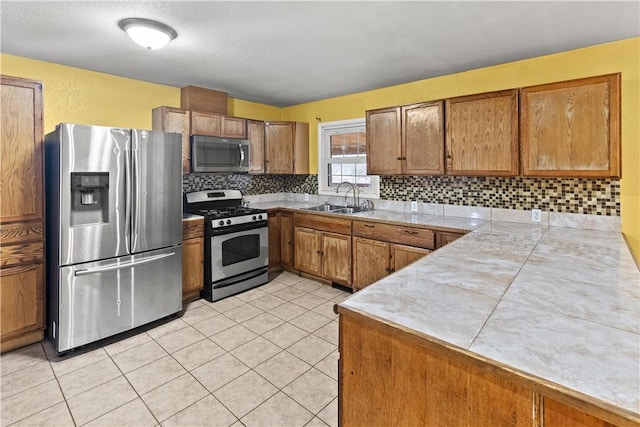 kitchen featuring tasteful backsplash, sink, light tile patterned floors, and appliances with stainless steel finishes