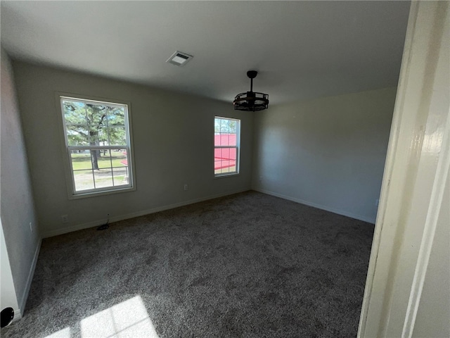 unfurnished room featuring carpet floors, baseboards, a chandelier, and visible vents