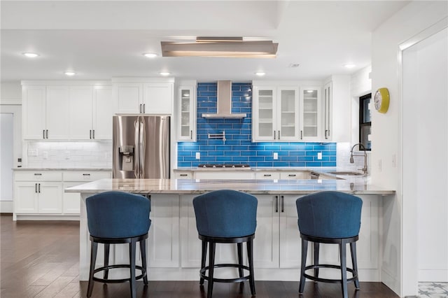 kitchen with sink, a breakfast bar area, white cabinetry, light stone counters, and stainless steel fridge with ice dispenser