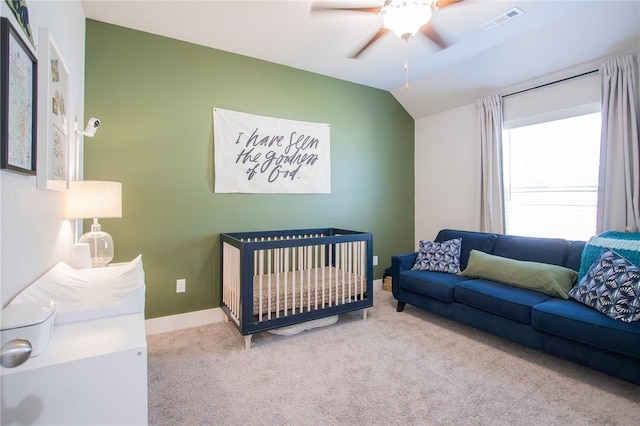 carpeted bedroom featuring visible vents, vaulted ceiling, ceiling fan, a nursery area, and baseboards