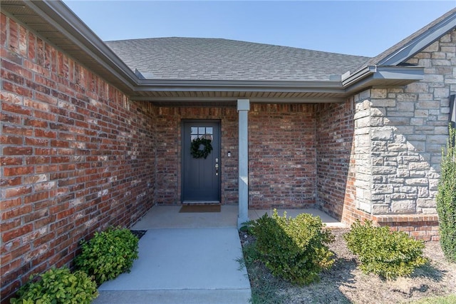 property entrance featuring brick siding and roof with shingles