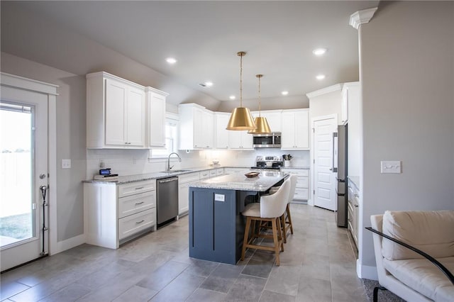 kitchen featuring a center island, stainless steel appliances, tasteful backsplash, white cabinets, and a sink