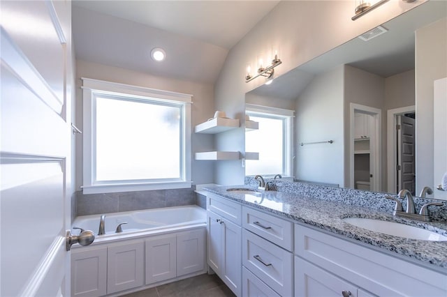 bathroom featuring double vanity, a garden tub, visible vents, and a sink