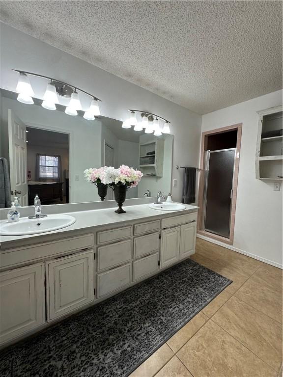 bathroom featuring vanity, tile patterned flooring, a shower with door, and a textured ceiling