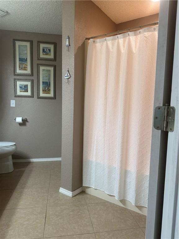 bathroom with tile patterned floors, toilet, and a textured ceiling