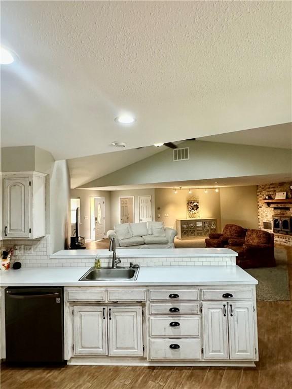 kitchen featuring sink, hardwood / wood-style flooring, black dishwasher, white cabinets, and vaulted ceiling