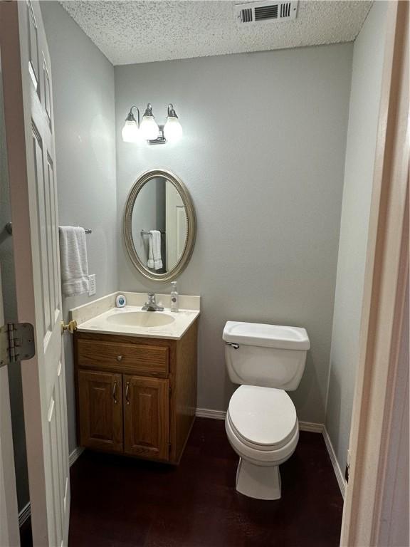 bathroom featuring vanity, a textured ceiling, wood-type flooring, and toilet