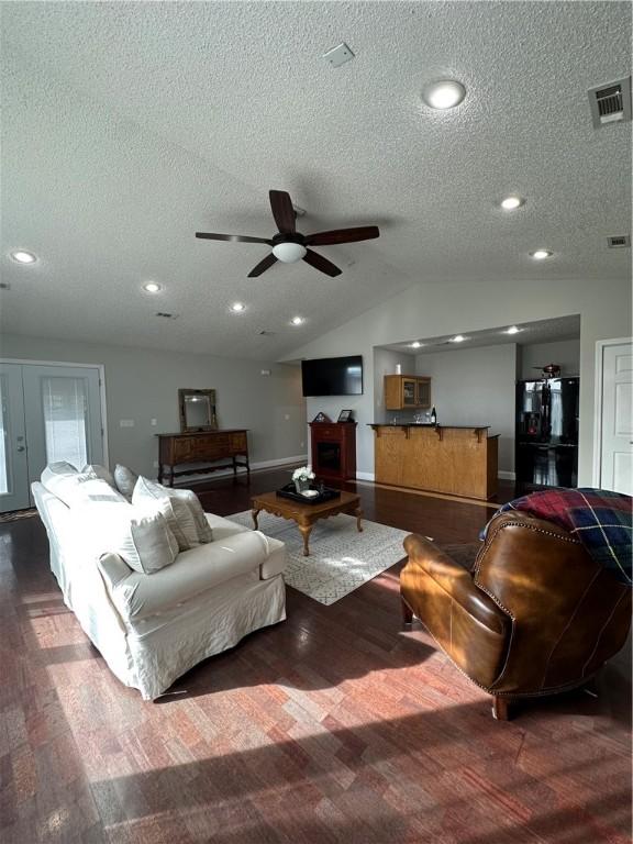 living room featuring vaulted ceiling, ceiling fan, a textured ceiling, and dark hardwood / wood-style flooring