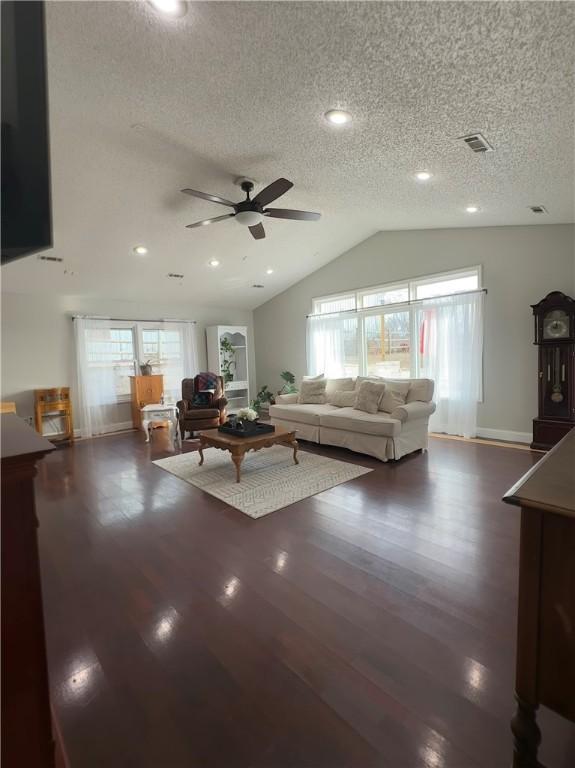 unfurnished living room with ceiling fan, dark hardwood / wood-style floors, vaulted ceiling, and a wealth of natural light