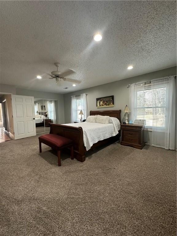 carpeted bedroom featuring ceiling fan and a textured ceiling