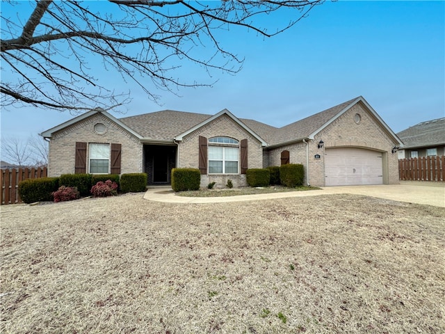 ranch-style home featuring fence, concrete driveway, an attached garage, a shingled roof, and brick siding