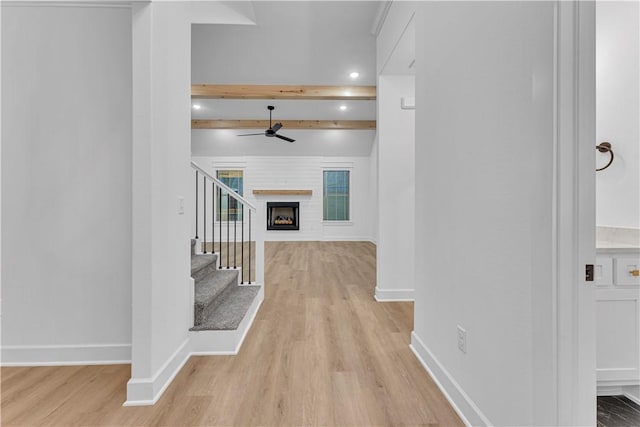 entrance foyer with ceiling fan, light hardwood / wood-style floors, a large fireplace, and beamed ceiling