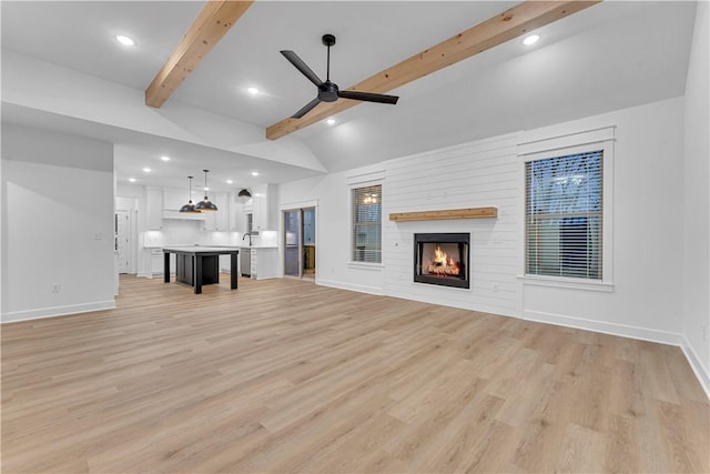 unfurnished living room featuring ceiling fan, vaulted ceiling with beams, a fireplace, and light wood-type flooring