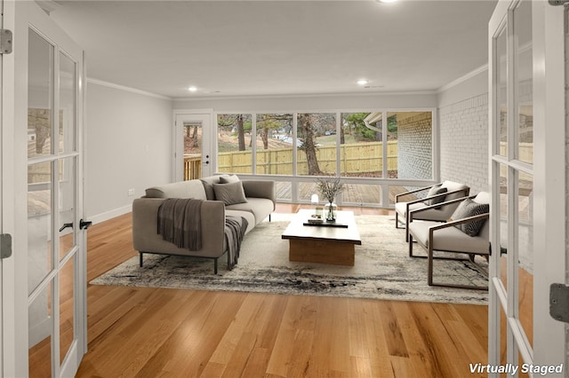 living room featuring french doors, ornamental molding, and light hardwood / wood-style floors