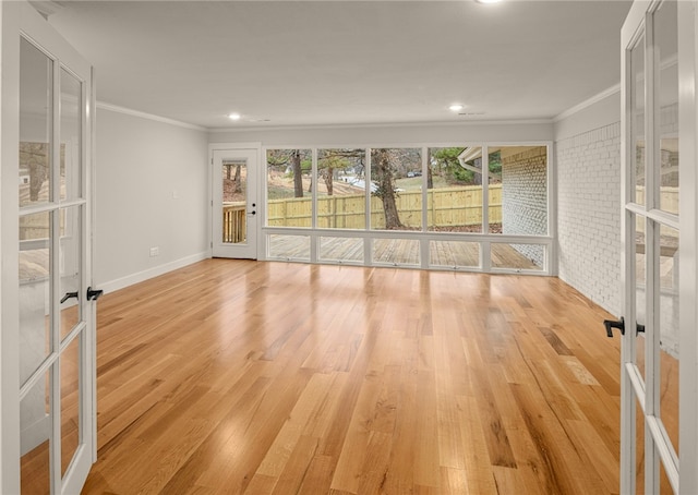 empty room with french doors, brick wall, ornamental molding, and light wood-type flooring