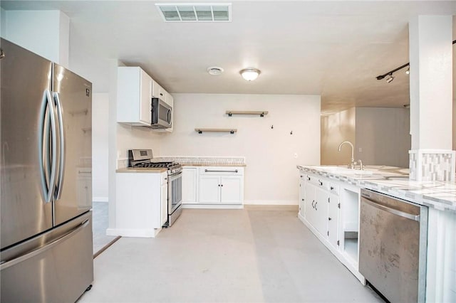 kitchen with appliances with stainless steel finishes, light stone countertops, sink, and white cabinets