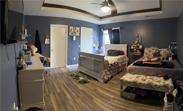 bedroom featuring hardwood / wood-style floors, ceiling fan, and a tray ceiling