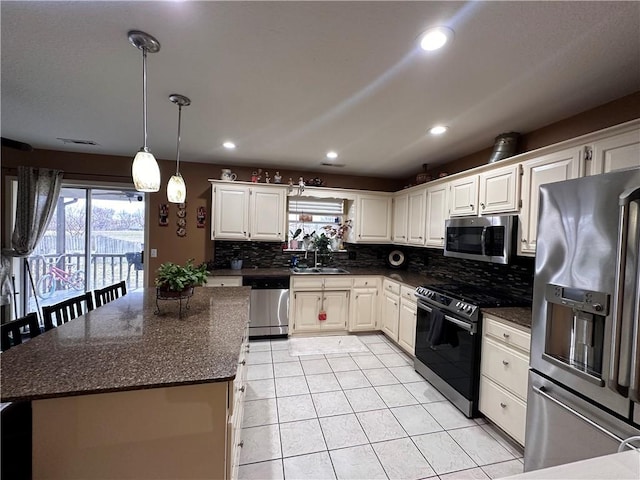 kitchen featuring sink, white cabinetry, appliances with stainless steel finishes, a kitchen island, and decorative backsplash