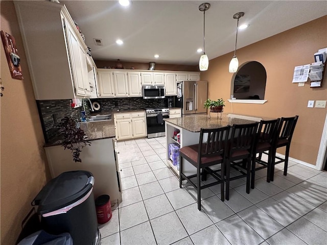 kitchen featuring sink, a kitchen island, white cabinets, stainless steel appliances, and backsplash