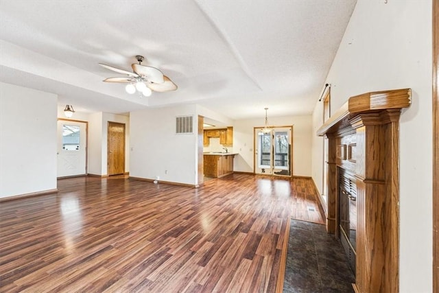 unfurnished living room with a textured ceiling, dark hardwood / wood-style floors, and ceiling fan