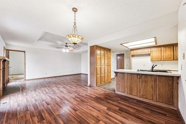 kitchen featuring dark hardwood / wood-style floors, kitchen peninsula, sink, and a textured ceiling