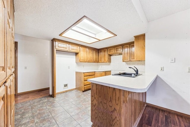 kitchen featuring sink, backsplash, a textured ceiling, and kitchen peninsula