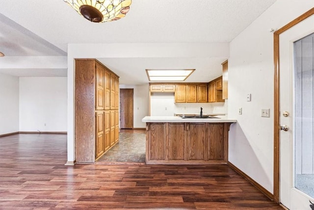 kitchen with dark wood-type flooring, sink, a textured ceiling, and kitchen peninsula