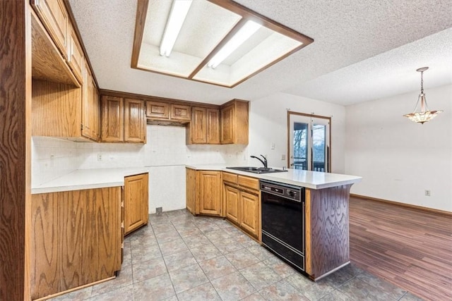 kitchen featuring sink, a textured ceiling, dishwasher, kitchen peninsula, and pendant lighting