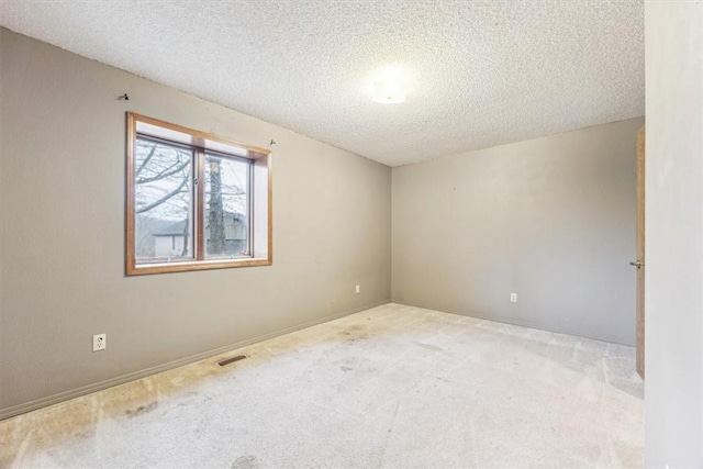 carpeted empty room featuring a textured ceiling