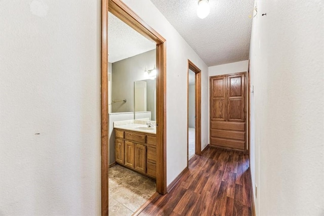 hall with dark hardwood / wood-style flooring, sink, and a textured ceiling