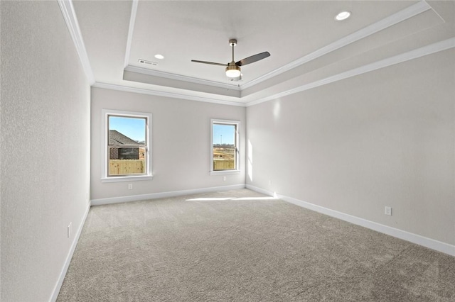 carpeted spare room with a raised ceiling, ornamental molding, and ceiling fan