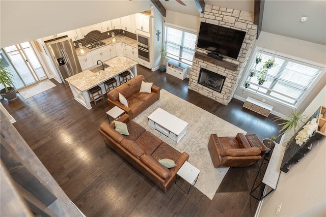 living room featuring sink, a stone fireplace, and dark hardwood / wood-style floors