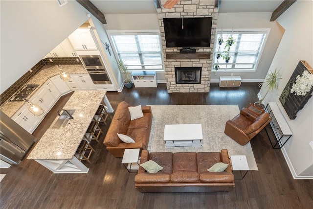 living room featuring beam ceiling, plenty of natural light, dark hardwood / wood-style floors, and a fireplace