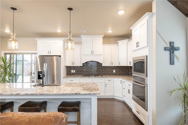 kitchen featuring hanging light fixtures, white cabinets, and appliances with stainless steel finishes