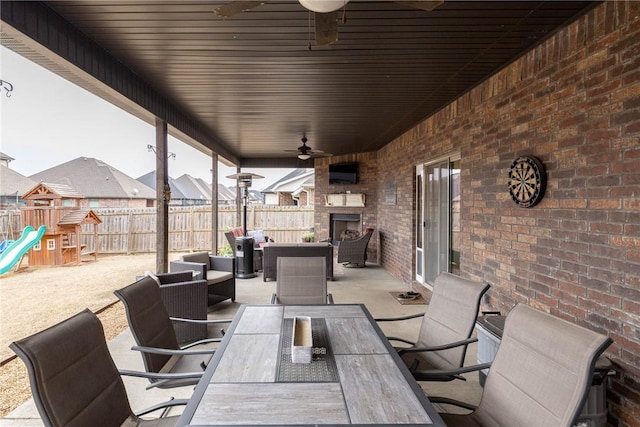 view of patio / terrace with ceiling fan, an outdoor fireplace, and a playground