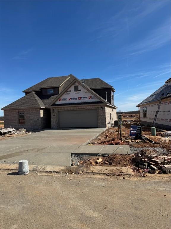 property in mid-construction with driveway, a garage, and brick siding