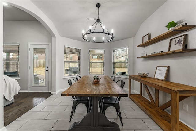 dining room featuring vaulted ceiling, an inviting chandelier, and light hardwood / wood-style floors