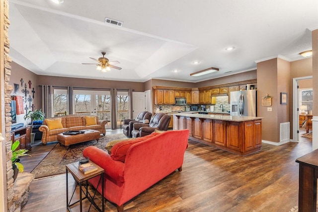 living room with dark hardwood / wood-style floors, a tray ceiling, sink, and crown molding