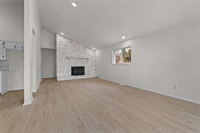 unfurnished living room with lofted ceiling, a fireplace, and light hardwood / wood-style flooring