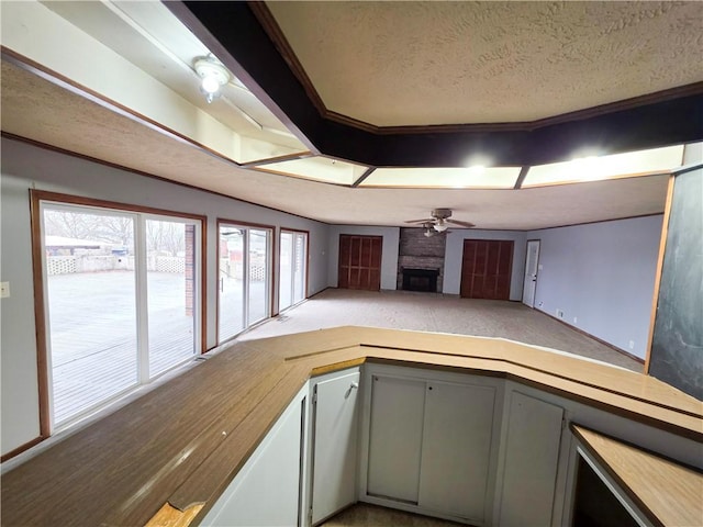 kitchen with ceiling fan, gray cabinetry, a fireplace, a textured ceiling, and kitchen peninsula